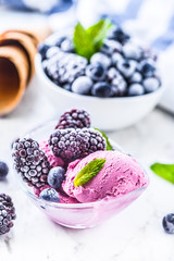 Blueberry and blackberry ice cream in bowl with frozen fruits