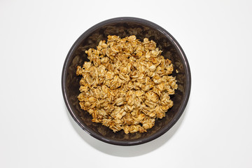 Obraz na płótnie Canvas delicious tasty granola with oats flakes fried in honey in the little brown bowl isolated on white background