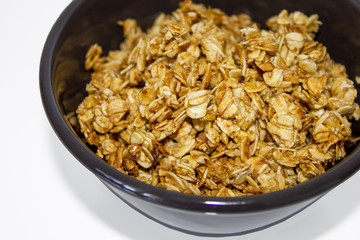 delicious tasty granola with oats flakes fried in honey in the little brown bowl isolated on white background