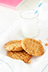 Delicious homemade peanut butter cookies with mug of milk. White wooden background. Healthy snack or tasty breakfast concept.