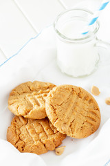 Delicious homemade peanut butter cookies with mug of milk. White wooden background. Healthy snack or tasty breakfast concept.