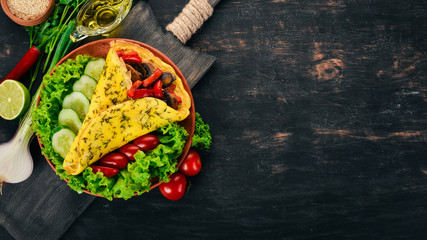 Omelet with mushrooms and vegetables. Fried eggs. On a wooden background. Top view. Free copy space.