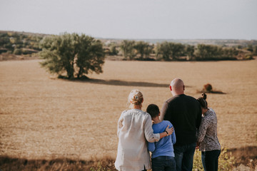 A happy family is standing in the nature at sunset i