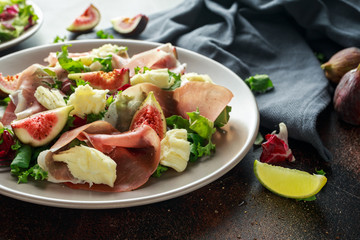 Fresh figs salad with prosciutto, green mix and cheese in a plate