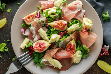 Fresh figs salad with prosciutto, green mix and cheese in a plate