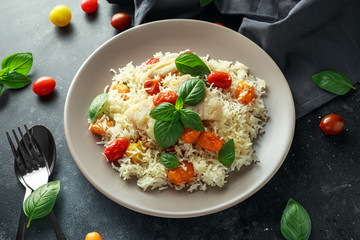 Steamed cod fish with rice and cherry mix tomatoes and basil herbs in a plate
