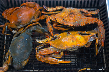 Many grilled crabs on grill.