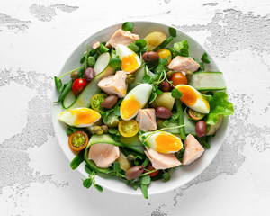 Healthy Nicoise salad with salmon, colourful sweet cherry tomatoes, olives, green beans, cucumber...