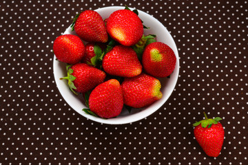 Fresh strawberry in a white plate on table, top view.