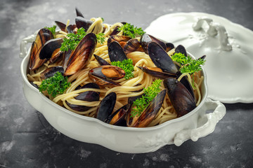 White wine and garlic steamed mussels with pasta served with parsley in white vintage tureen