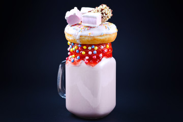 Pink strawberry freakshake with marshmallow and sweets.