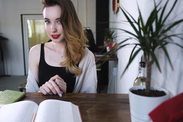 The girl sits at the table in front of an open book, on the right there is free space for writing.