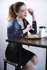 Girl with red lipstick on her lips sitting at a high table with cake and coffee.