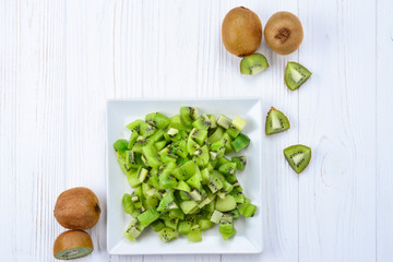 Freshly sliced kiwi fruit with whole kiwis in background.