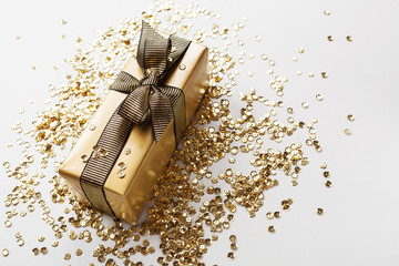 Gift or present box decorated golden sequins on table. Greeting card for Christmas or birthday.