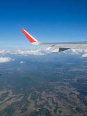 View from airplane windows from passenger, beautiful cloud group, blue sky and landscape. Wing aircraft in altitude during flight.Concept of travel and business trip. Traveling concept.