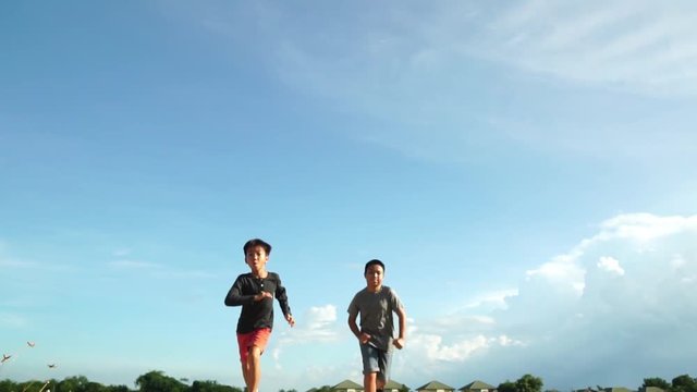 Slow motion of young Asian boy run and jump under blue sky in summer