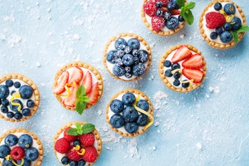 Foto op Plexiglas Gezond zomers gebakdessert. Berry tartlets of cake met roomkaas bovenaanzicht. © juliasudnitskaya