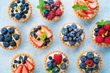 Obraz na płótnie Canvas Berry tartlets background. Delicious summer pastry dessert top view.
