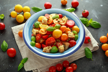 Panzanella Tomato salad with red, yellow, orange cherry tomatoes, capers, basil and ciabatta croutons. summer healthy food.