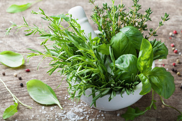 Aromatic herbs in mortar bowl. Basil, thyme, rosemary and tarragon. Fresh ingredients for cooking.