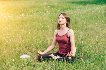 Beautiful girl doing yoga into the park. Relax, rest, harmony
