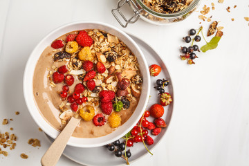 Smoothie bowl with banana, cocoa, berries and homemade granola, top view. Healthy vegan food concept.