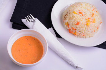 White plate with sauce in a bowl and risotto flat lay