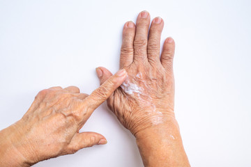 Senior Woman applying moisturizing cream on her hands isolated on white background, Beauty concept skin