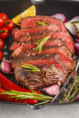Sliced roast beef in a frying pan with spices and vegetables, white background, macro