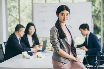 smart and attractive asian designer woman look and smile to camera in meeting room office background