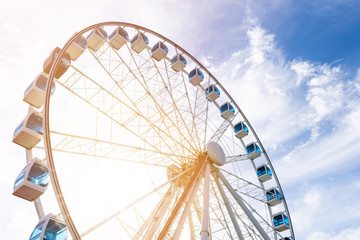 Low angle view of a ferris wheel in an amusement park with a blue sky background. City park ferris wheel in Carousel Gardens. Holiday concept