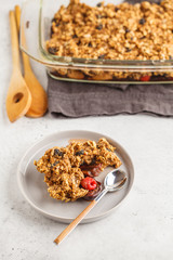 Crumble cake with plum and raspberries in a glass dish, white background. Healthy vegan food concept.