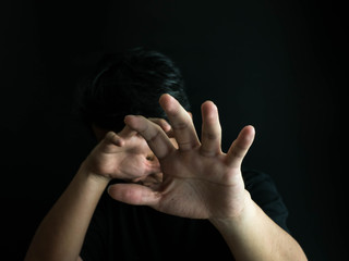 Fototapeta premium Scared man put his hands forward. Man with emotion of fear isolated on black background. concept human behavior