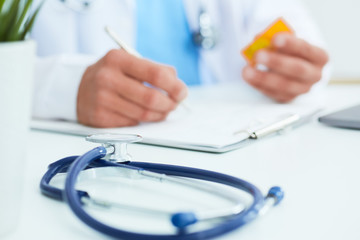 Male physician medicine doctor or pharmacist sitting at worktable, holding jar or bottle of pills...