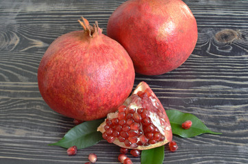Red juicy fruit pomegranate with red seeds on black wooden background
