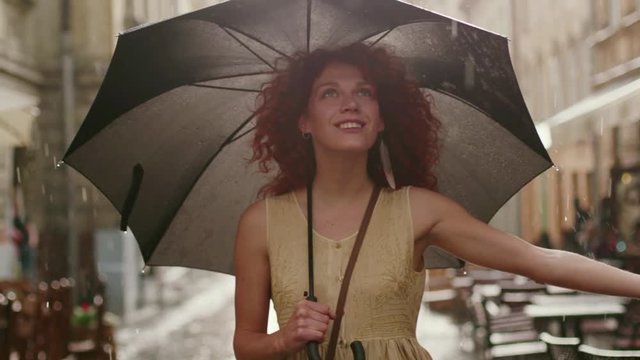 Close up smiling attractive woman with red curly hair walking on the street with umbrella happy cute fashion water silhouette girl summer face female portrait slow motion