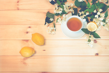 Green tea, lemon and jasmine flowers on wooden background. Top view, copy space. Toned image.