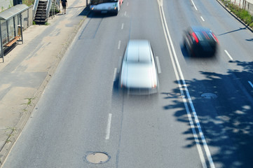 Rozmyte sylwetki samochodów podczas jazdy na dwupasmowej jezdni. - obrazy, fototapety, plakaty