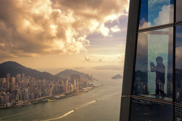 Young man traveler take a photo of Hong Kong City skyline at sunset  from sky 100 Hongkong.