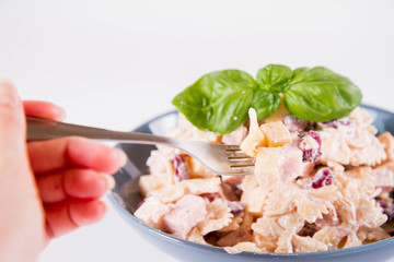 Pasta salad with cheese, ham, kidney beans and mayonnaise eaten with a fork