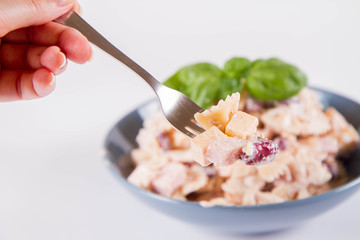 Pasta salad with cheese, ham, kidney beans and mayonnaise eaten with a fork