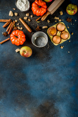 Sweet autumn baking cooking background with flour, rolling pin, decorative pumpkins, apples, cinnamon spices with anise cardamom sugar. Dark blue rusty background top view copy space