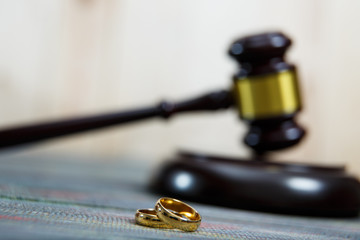 Closeup of wedding rings on wooden mallet at table in courtroom