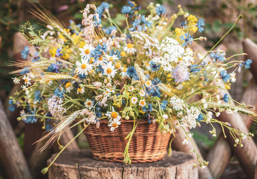 Wild flowers in a basket on a rustic background. Vintage scenery.