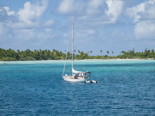 Naklejka premium sailing yacht anchoring in the shallow, turquoise lagoon of Fakarava atoll, Tuamotus archipelago, French Polynesia, south pacific