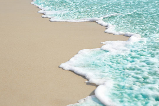 Soft wave and sea bubble of blue sea on sandy beach
