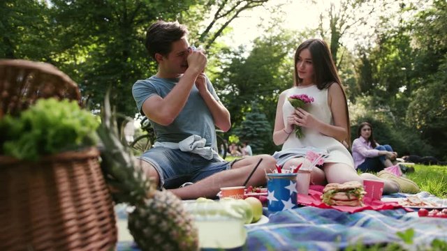couple smiling resting in park have picnic talk drink man take photo on polaroid woman tree love girl summer nature beautiful emotive outdoors outing pleasure positive pretty relations slow motion