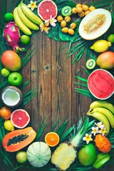 Fotobehang Assortment of tropical fruits with leaves of palm trees and exotic plants on dark wooden background © Alexander Raths
