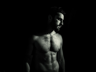 Handsome young muscular man shirtless, on black background in studio shot
